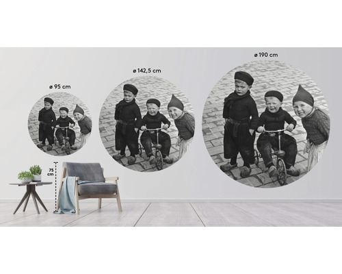 Tri okrúhle nástenné dekorácie s historickou fotografiou troch hrajúcich sa detí v rôznych veľkostiach v miestnosti.