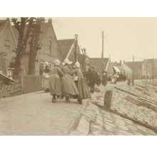 Historická fotografia pouličnej scény s ľuďmi v tradičnom oblečení pred domami