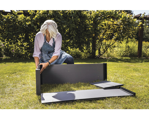 Žena zostavuje vyvýšený záhon v záhrade.