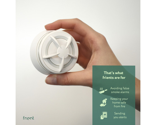 Ruka drží biely hlásič dymu značky Frient