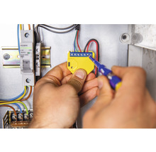 Elektrikár montuje elektronický komponent pomocou skrutkovača do rozvodnej skrine