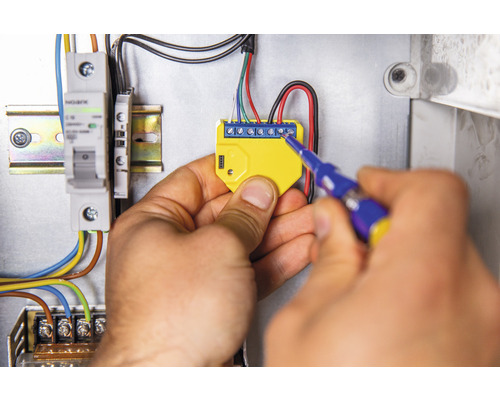 Elektrikár montuje elektronický komponent pomocou skrutkovača do rozvodnej skrine