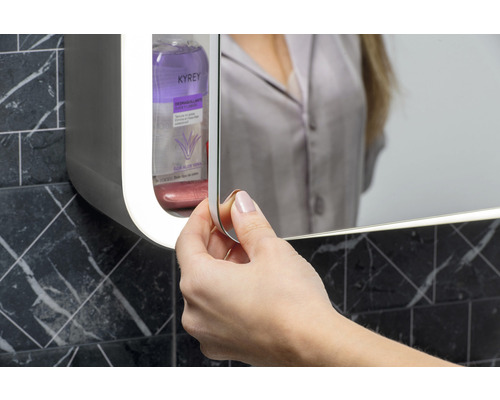 Žena otvára zrkadlovú skrinku v kúpeľni