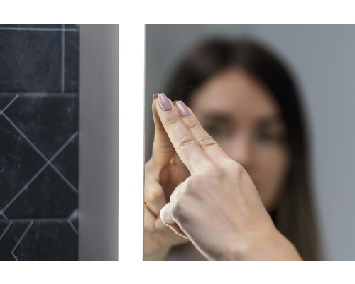 Žena sa dotýka osvetleného kúpeľňového zrkadla