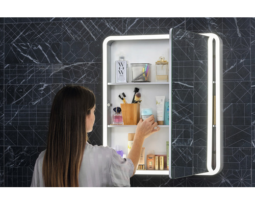 Žena pred zrkadlovou skrinkou s osvetlením v kúpeľni