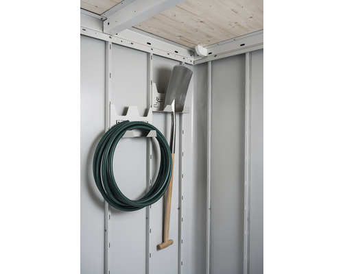 Záhradná hadica a rýľ na držiaku náradia v záhradnom domčeku