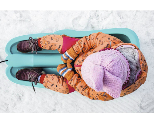 Dieťa leží na saniach v snehu.