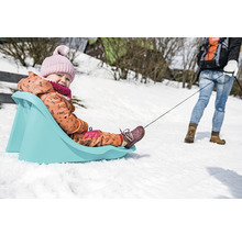 Dieťa na plastových saniach ťahá osoba v snehu