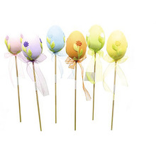 Dekoratívne veľkonočné vajíčka na tyčkách s kvetinovými motívmi a stuhami.