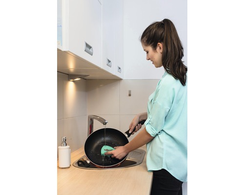 Žena umýva panvicu v kuchynskom dreze