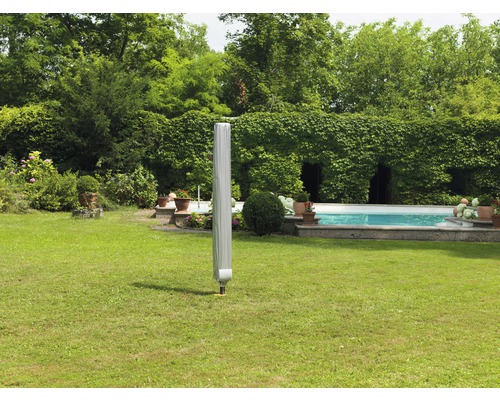 Uzavretý záhradný slnečník s ochranným obalom na trávniku v záhrade s bazénom