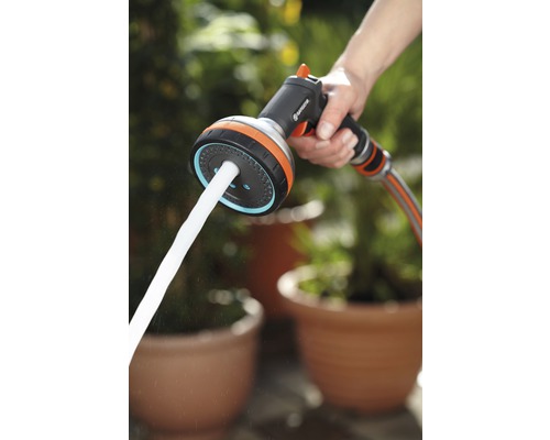 Zavlažovacia pištoľ s prúdom vody v ruke.