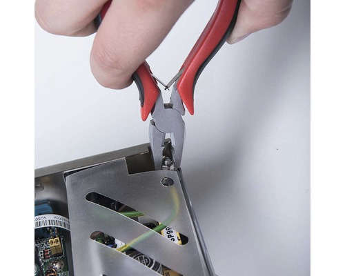 Kliešte strihajú súčiastku z elektronického zariadenia.