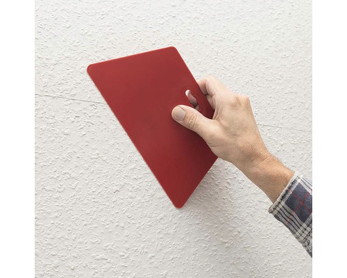 Ruka s červenou špachtľou na stene