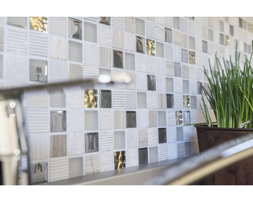 Detail steny s mozaikovými obkladmi a črepníkovou rastlinou.