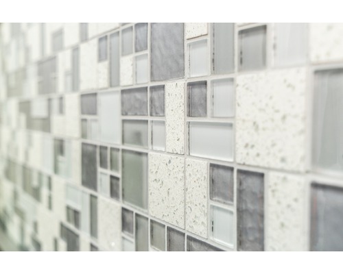 Detailný záber steny s mozaikovými obkladmi v rôznych odtieňoch šedej a textúrach.