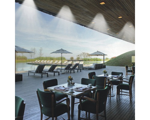 Vonkajší priestor so stolmi, stoličkami, slnečníkmi a ležadlami pri jazere