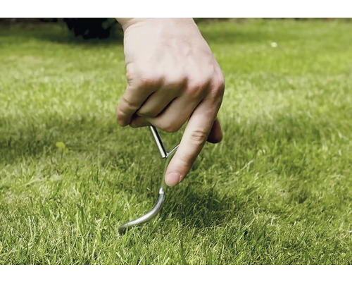 Ruka zapichuje kolík do trávnika