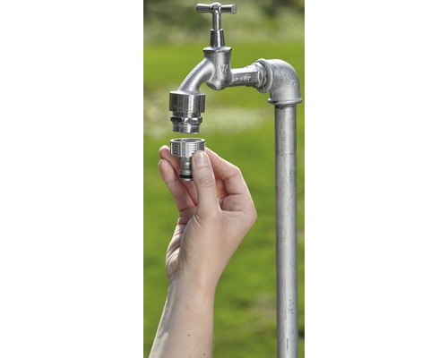 Ruka montuje hadicovú spojku na záhradný vodovodný kohútik.