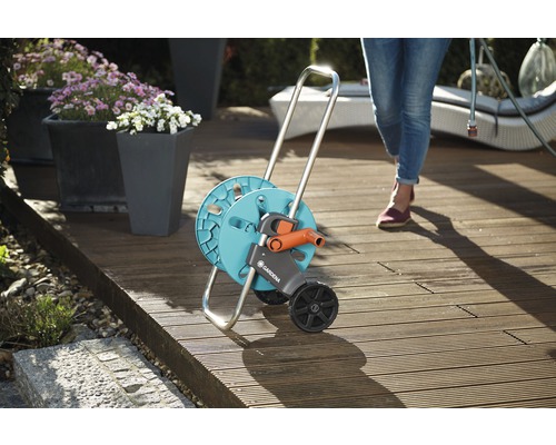 Vozík na záhradnú hadicu s kolieskami na drevenej terase