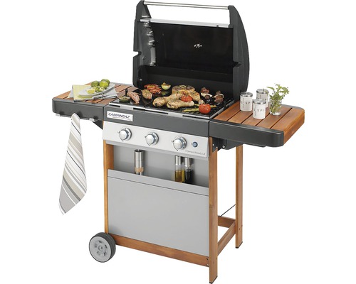 Plynový gril s jedlom na grilovacej mriežke a bočnými policami.