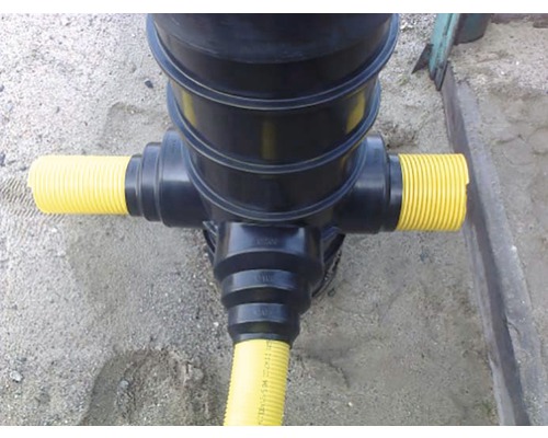 Pohľad zhora na čierny odtok dažďovej vody so žltými rúrami