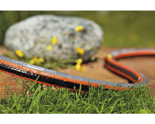 Záhradná hadica Gardena na trávniku s kameňom v pozadí