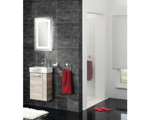 Moderná kúpeľňa s umývadlom, osvetleným zrkadlom a tmavými obkladmi