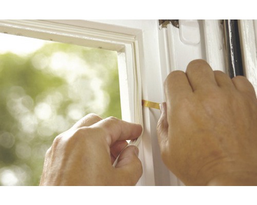 Osoba utesňuje okno tesniacou páskou.