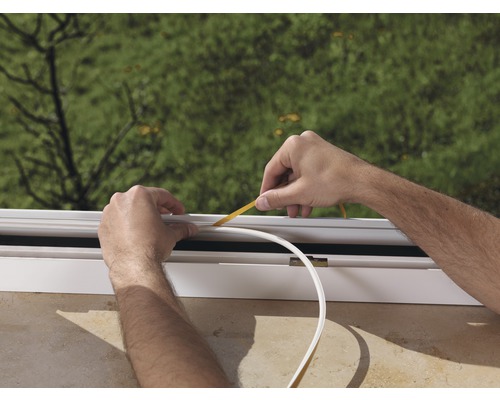 Osoba pripevňuje tesniacu pásku na okno