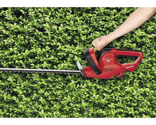 Osoba používa červené nožnice na živý plot Einhell na strihanie živého plota.