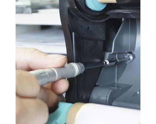 Ruka skrutkuje skrutku do zariadenia pomocou skrutkovača