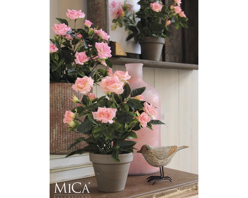 Dekoratívne ruže v kvetináči na stole s drevenou dekoráciou v tvare vtáka a vázou.