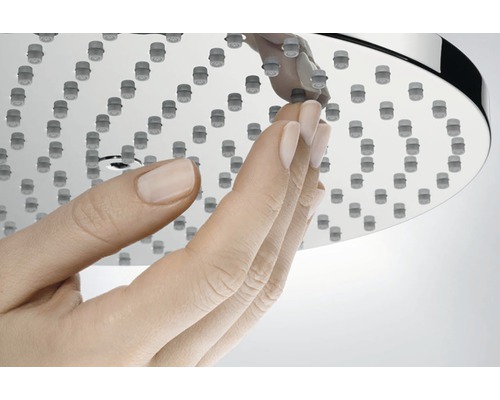 Ruka sa dotýka sprchovej hlavice s funkciou proti usadzovaniu vodného kameňa