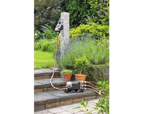 Záhradný zavlažovací systém so zavlažovacím počítačom, rozdeľovačom a zavlažovacími hadicami v záhrade