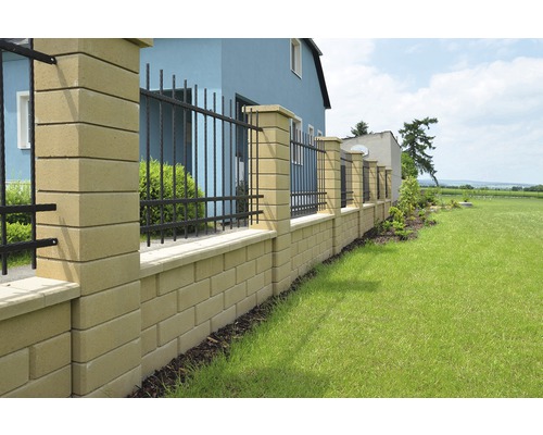 Betónový kamenný plot s kovovými prvkami v záhrade.