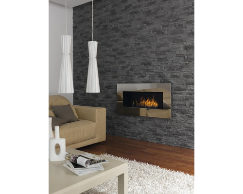 Obývacia izba s kamennou tapetou, krbom, pohovkou, stolom a dvoma závesnými svetlami