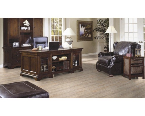 Kancelária so stolom, knižnicou, kreslom a otomanom v svetlej miestnosti.