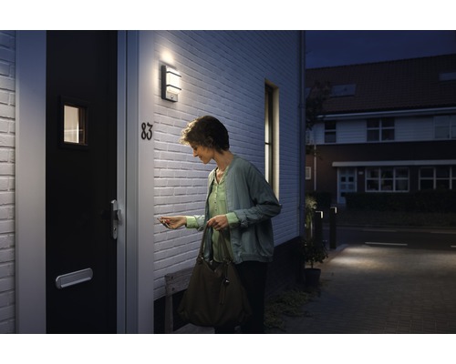 Žena odomyká vchodové dvere s vonkajším svetlom