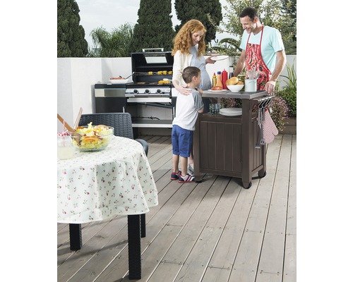 Rodina griluje vonku s plynovým grilom a grilovacím vozíkom na terase.