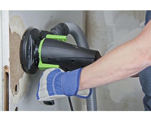 Remeselník brúsi stenu sadrokartónovou brúskou s odsávaním prachu