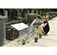 Scéna s fóliovým skleníkom a ženou, ktorá sadí kvety.