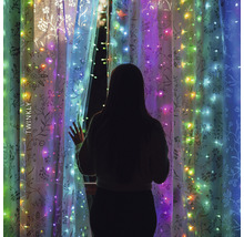 Žena stojí pred oknom s svetelnou reťazou Twinkly