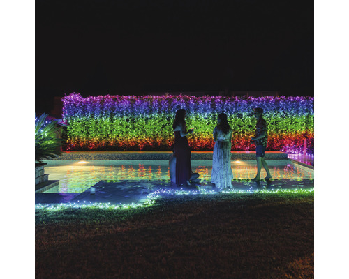 Scéna s ľuďmi pri bazéne osvetlená viacfarebnou svetelnou reťazou