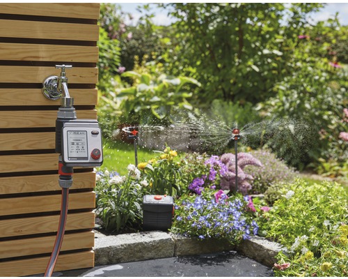 Riadiaca jednotka zavlažovania Gardena s vodovodným kohútikom a postrekovačmi v záhrade