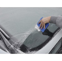 Ruka používa škrabku na ľad na zamrznutom čelnom skle automobilu