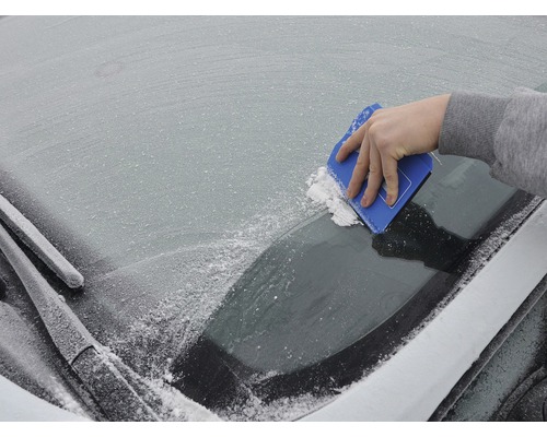 Ruka používa škrabku na ľad na zamrznutom čelnom skle automobilu