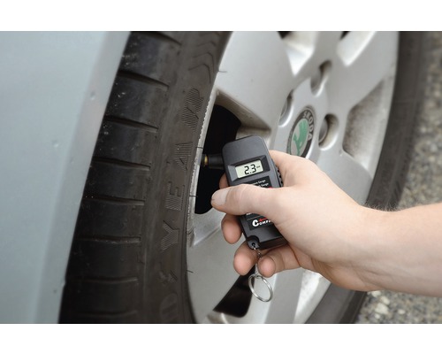 Ruka meria tlak v pneumatikách digitálnym manometrom na pneumatike.