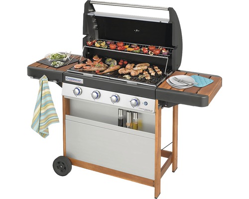 Plynový gril s jedlom na grilovacej mriežke a dvoma bočnými stolíkmi.