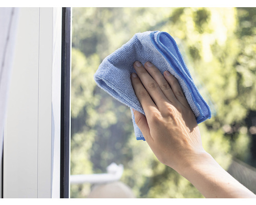 Ruka čistí okno handrou z mikrovlákna.